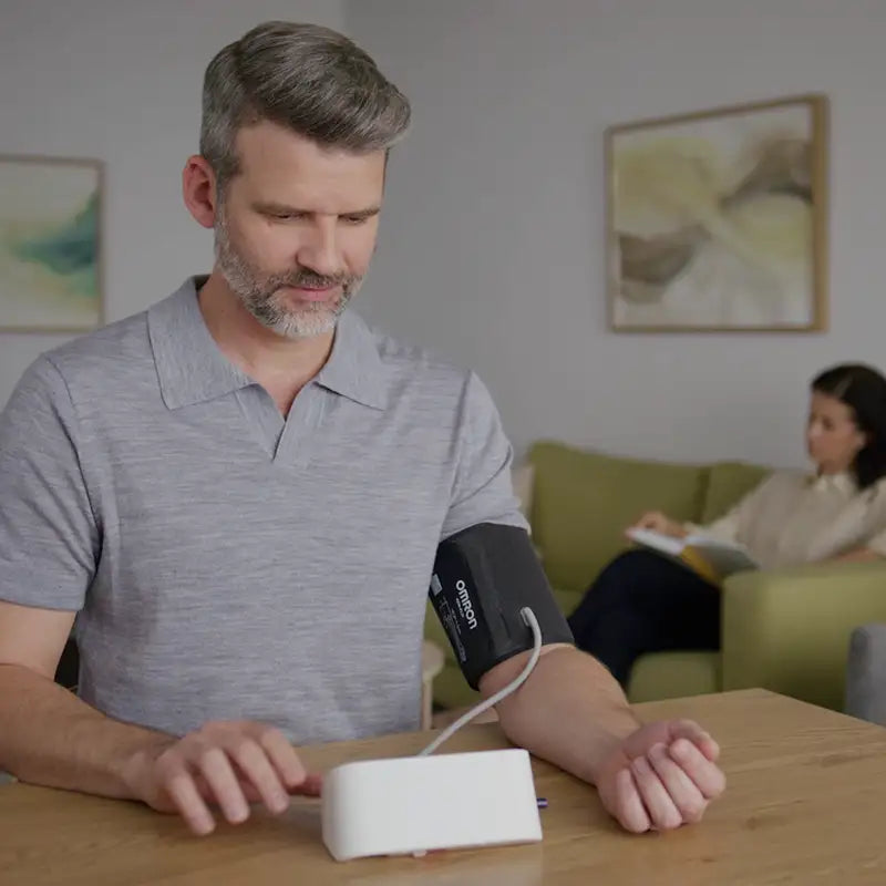 Man mäter blodtrycket hemma i vardagsrummet med Omron M4 Connect AFib