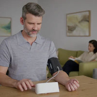 Man mäter blodtrycket hemma i vardagsrummet med Omron M4 Connect AFib