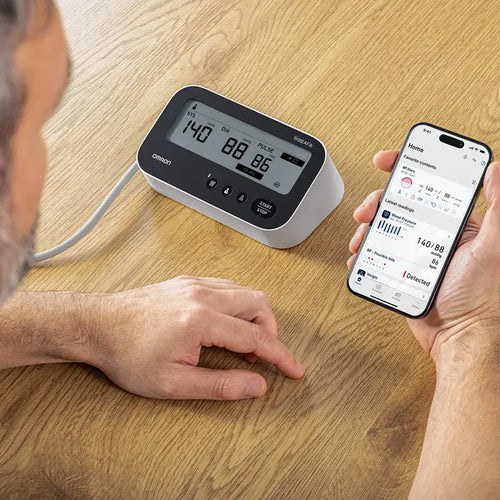 Man mäter blodtrycket med M4 Connect AFib  och  kontrollerar mätresultat i Connect-appen