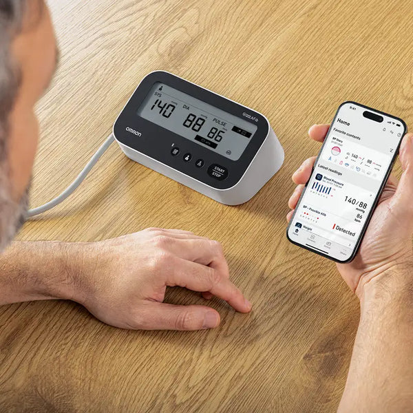 Man mäter blodtrycket med M4 Connect AFib  och  kontrollerar mätresultat i Connect-appen